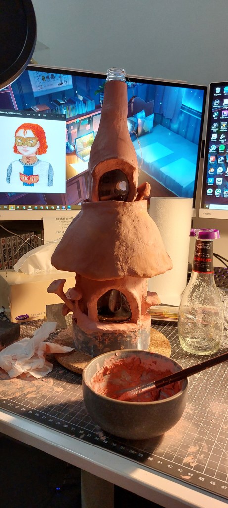 Fairy house made of layered clay over a bowl, jar and bottle. 